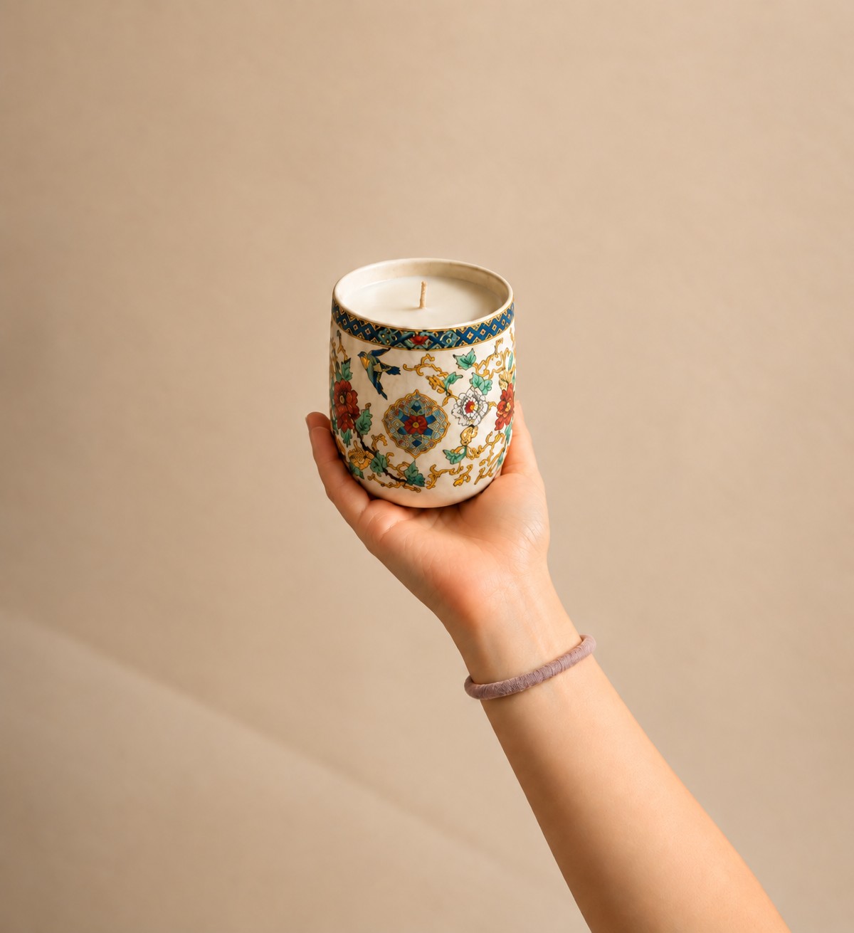 A porcelain vessel candle held in a hand